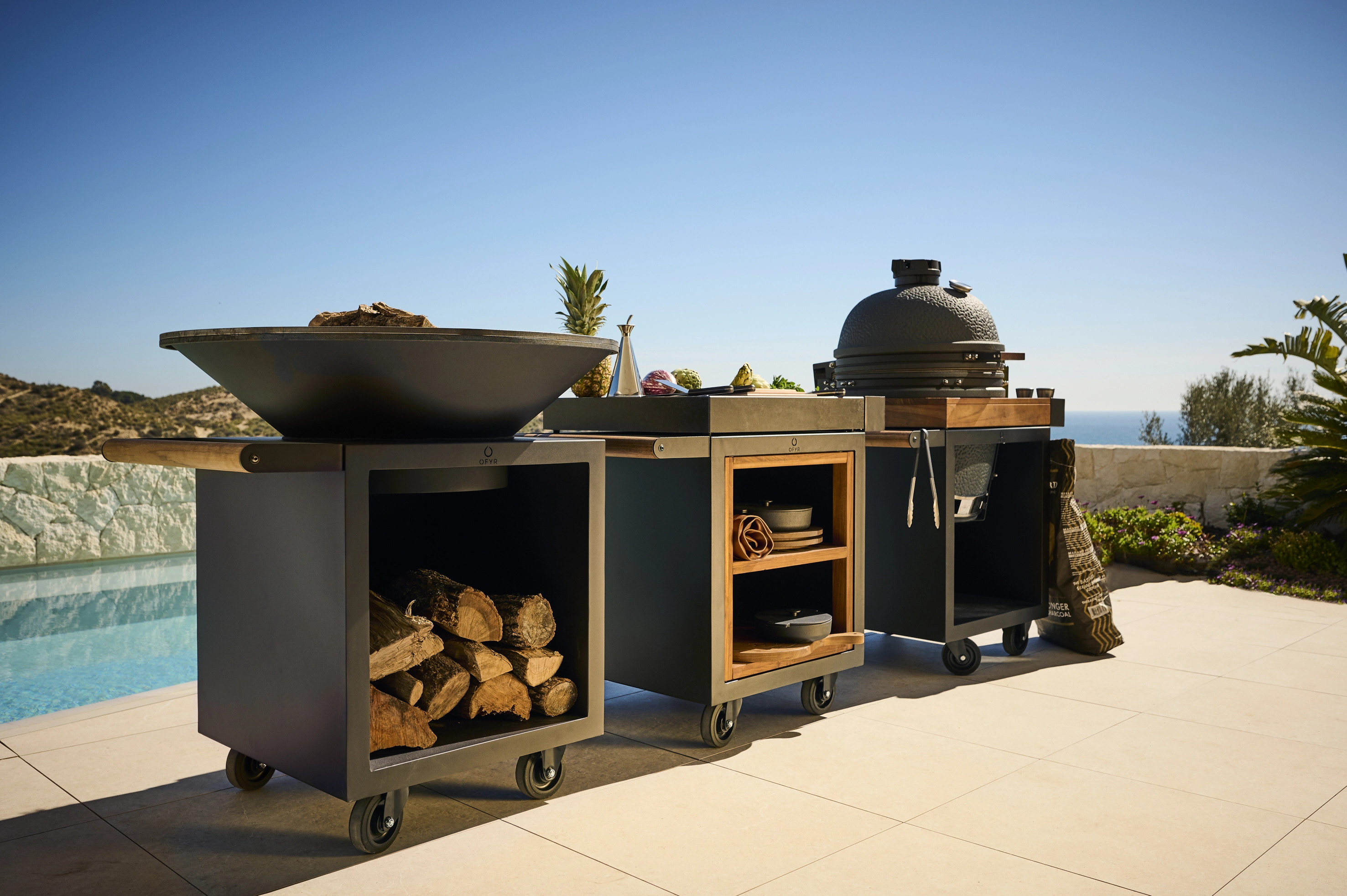 grill Ofyr Classic Pro, Kamado stół oraz Mise en Place na tle basenu na słonecznej wyspie